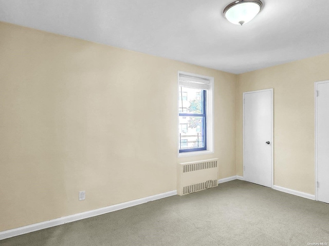 spare room with radiator and carpet