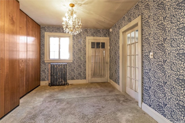 carpeted empty room featuring wood walls, french doors, radiator, and a chandelier