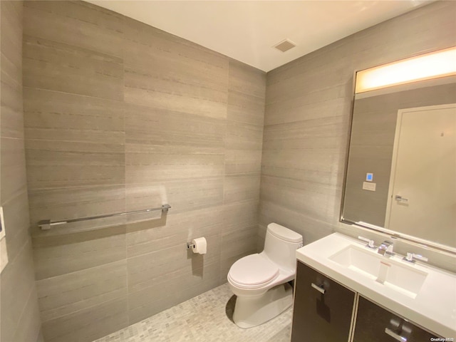 bathroom with tile patterned floors, vanity, toilet, and tile walls