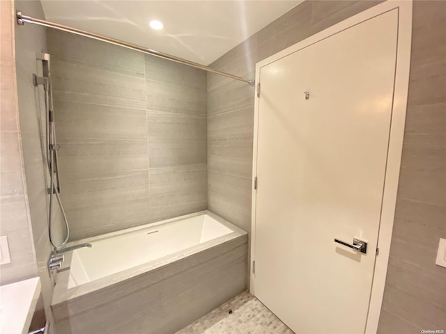 bathroom with tiled shower / bath combo and tile walls