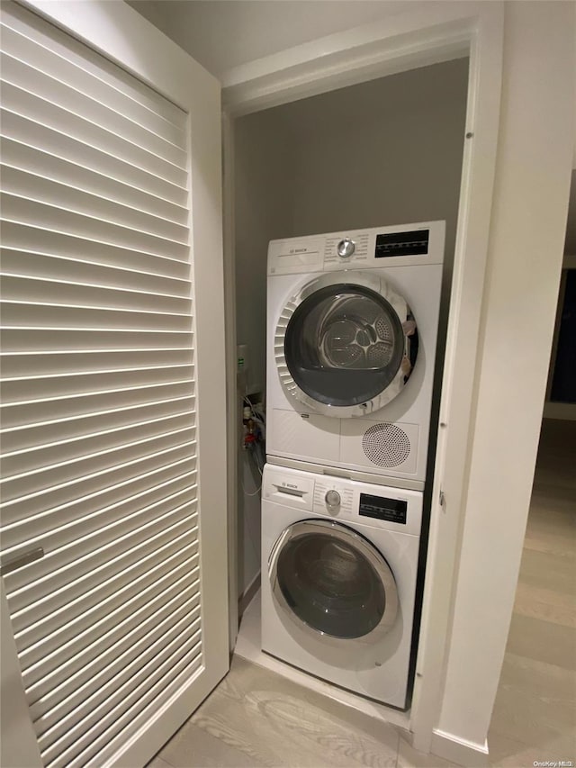 washroom with light hardwood / wood-style floors and stacked washer and clothes dryer