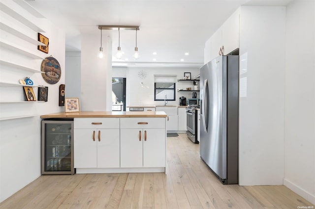 kitchen with white cabinets, wine cooler, pendant lighting, and appliances with stainless steel finishes