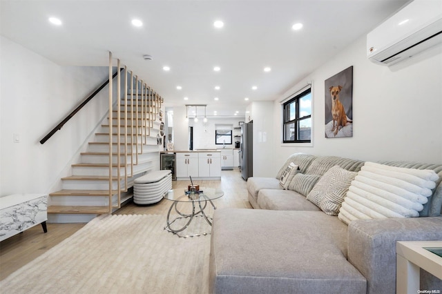 living room with a wall mounted AC, beverage cooler, and light wood-type flooring