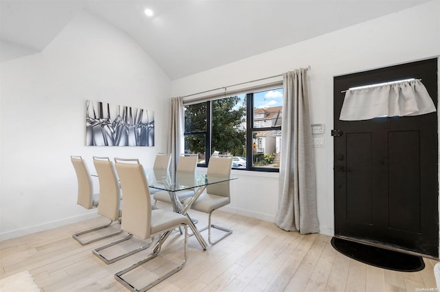 dining area with high vaulted ceiling and light hardwood / wood-style floors