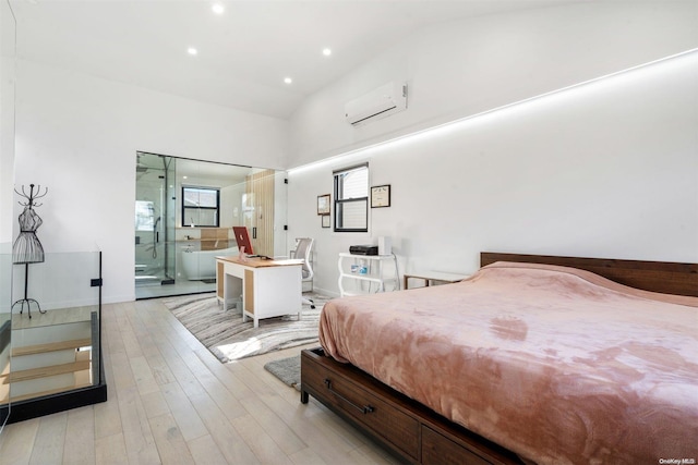 bedroom with light wood-type flooring, connected bathroom, a wall unit AC, and lofted ceiling