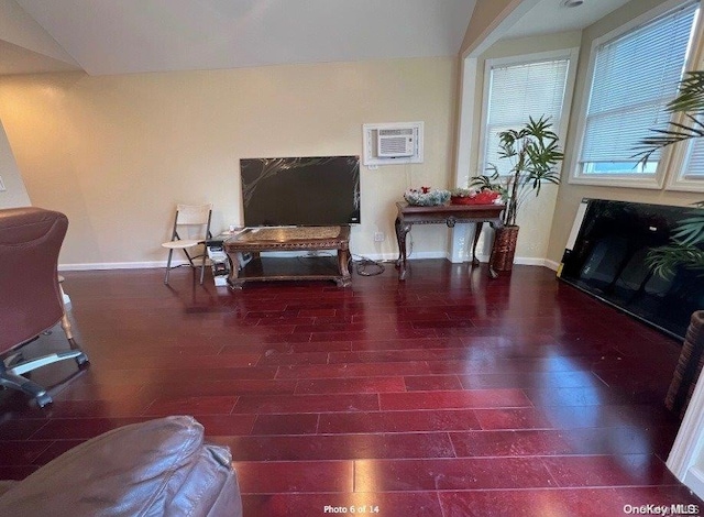 living room with dark hardwood / wood-style flooring, an AC wall unit, and vaulted ceiling