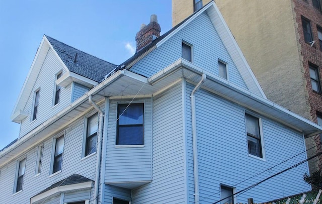 view of side of property with a shingled roof and a chimney