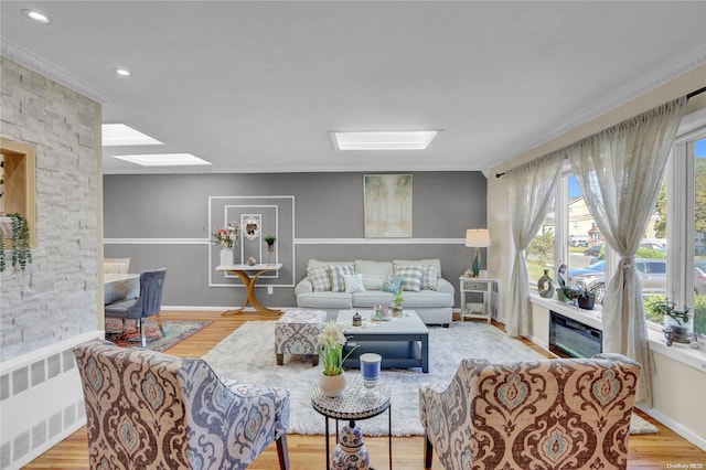 living room with radiator heating unit, light hardwood / wood-style flooring, and ornamental molding