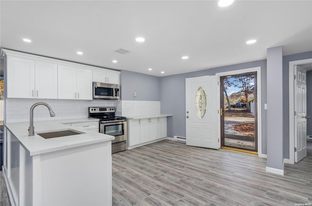 kitchen with light stone countertops, sink, light hardwood / wood-style floors, white cabinets, and appliances with stainless steel finishes