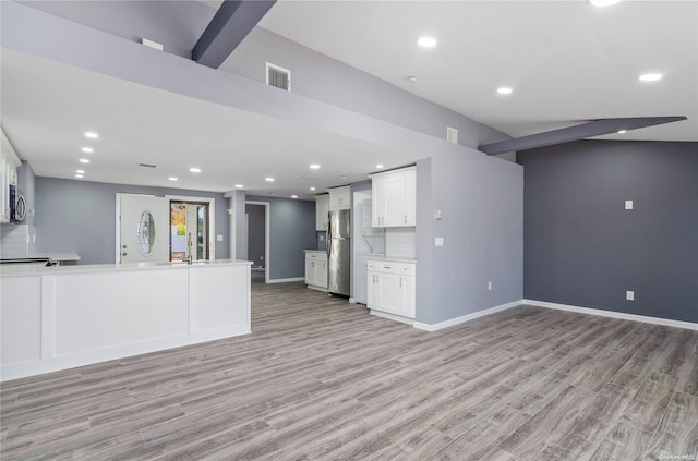 kitchen with sink, backsplash, stainless steel fridge, white cabinets, and light wood-type flooring