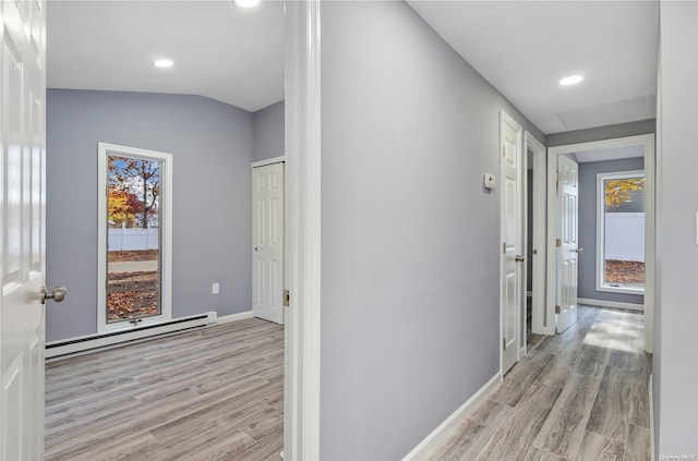 corridor with lofted ceiling, light hardwood / wood-style floors, and a baseboard heating unit