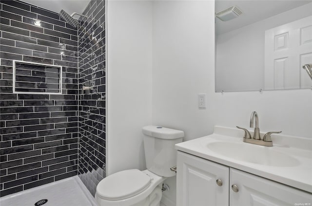 bathroom featuring tiled shower, vanity, and toilet