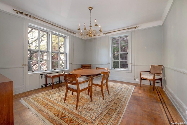 dining area featuring parquet floors, radiator, and a chandelier