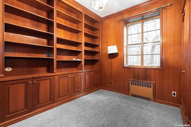 interior space with radiator heating unit, light colored carpet, and wood walls