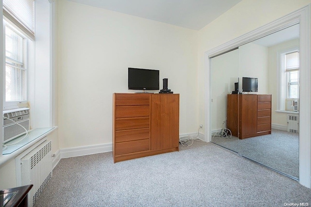 unfurnished bedroom with radiator, light colored carpet, and a closet