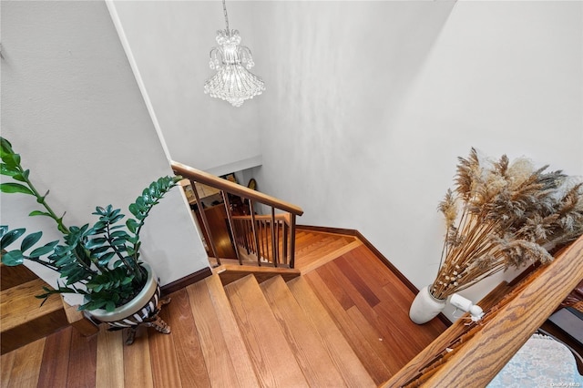 staircase featuring hardwood / wood-style floors and a chandelier