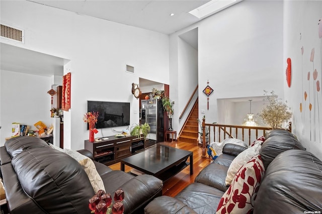 living room featuring a high ceiling, a skylight, and wood-type flooring