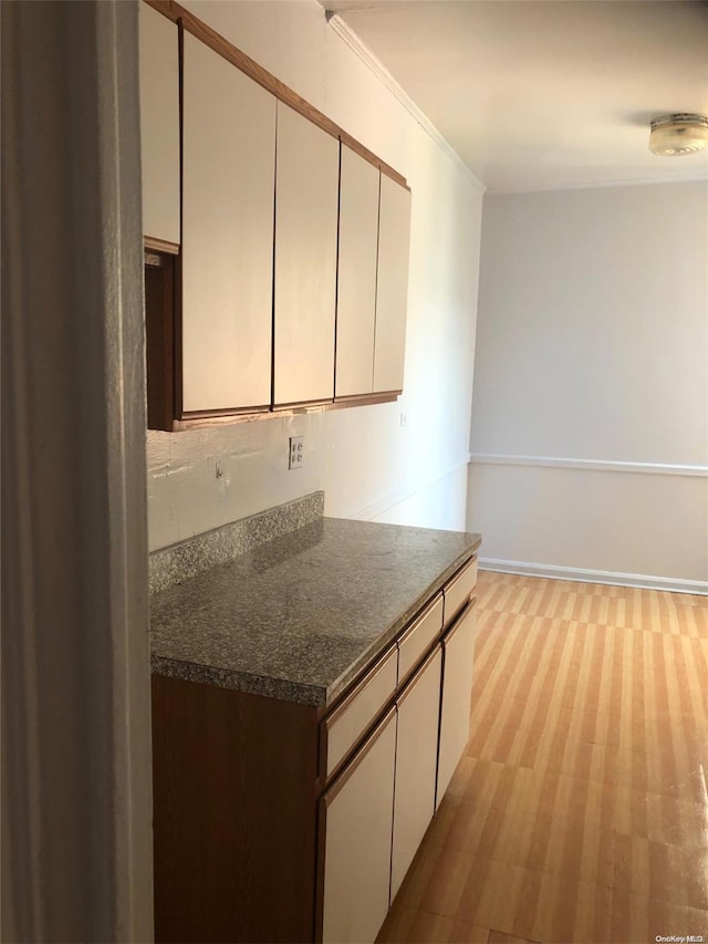 kitchen featuring white cabinetry, ornamental molding, and dark stone counters