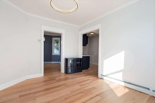 spare room with ornamental molding, baseboard heating, and light hardwood / wood-style floors