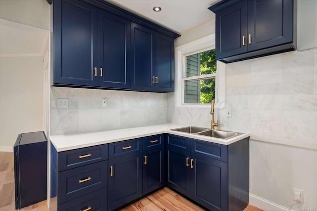 kitchen featuring blue cabinetry, tasteful backsplash, sink, and light hardwood / wood-style flooring