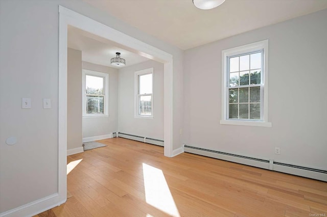 spare room featuring a baseboard heating unit and light hardwood / wood-style floors