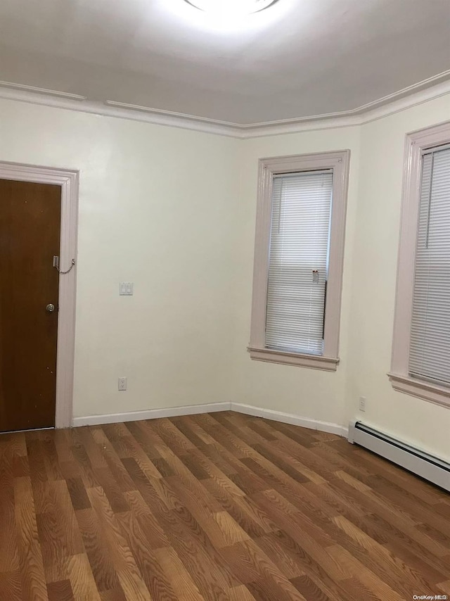 unfurnished room featuring ornamental molding, wood-type flooring, and a baseboard heating unit