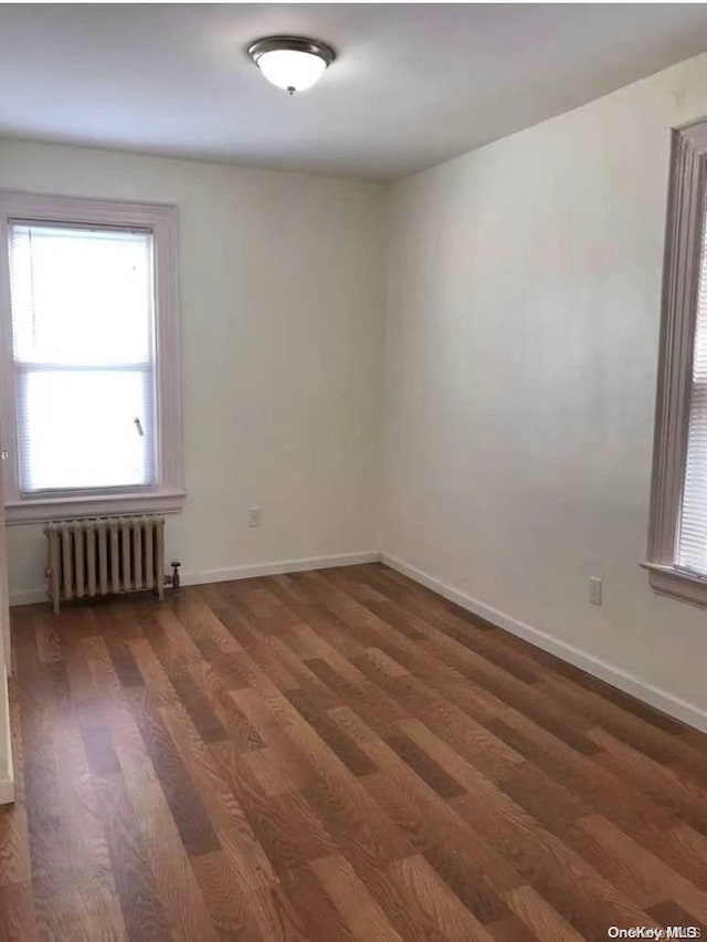 unfurnished room featuring radiator and dark wood-type flooring