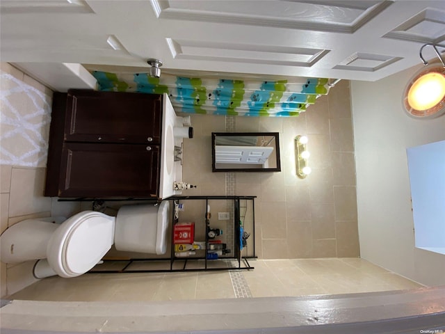 bathroom featuring tile patterned flooring, tile walls, and coffered ceiling