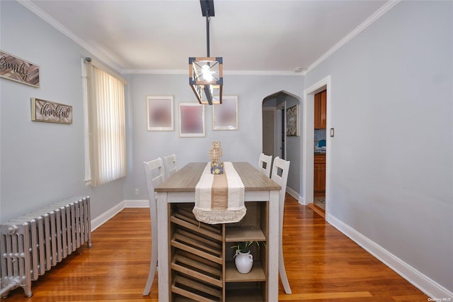 dining room with a chandelier, hardwood / wood-style flooring, radiator, and ornamental molding