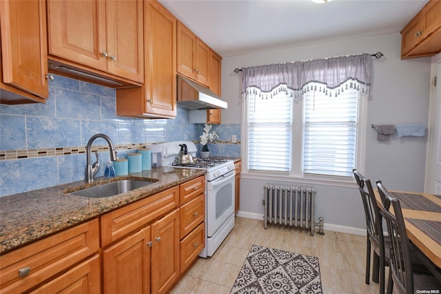 kitchen with dark stone counters, sink, decorative backsplash, white gas range, and radiator heating unit