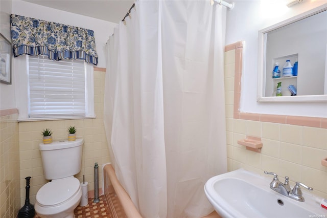 full bathroom with toilet, sink, and tile walls