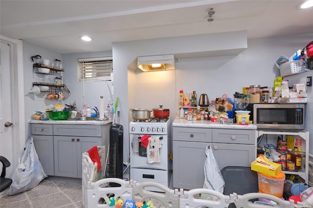 kitchen with light carpet, gray cabinetry, sink, white range with gas stovetop, and range hood