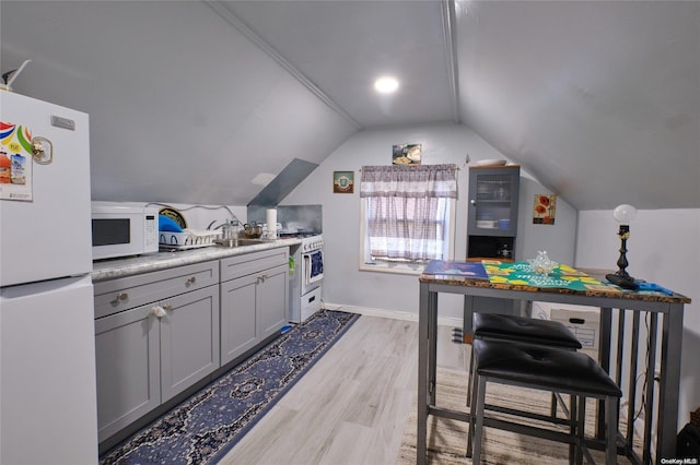 kitchen featuring gray cabinetry, light wood-type flooring, white appliances, and vaulted ceiling