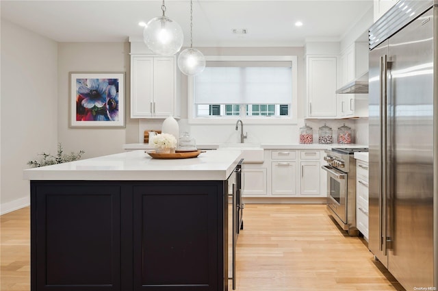 kitchen with pendant lighting, a center island, high quality appliances, and white cabinetry