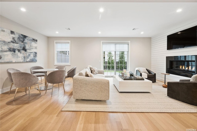 living room with a fireplace, light wood-type flooring, and plenty of natural light