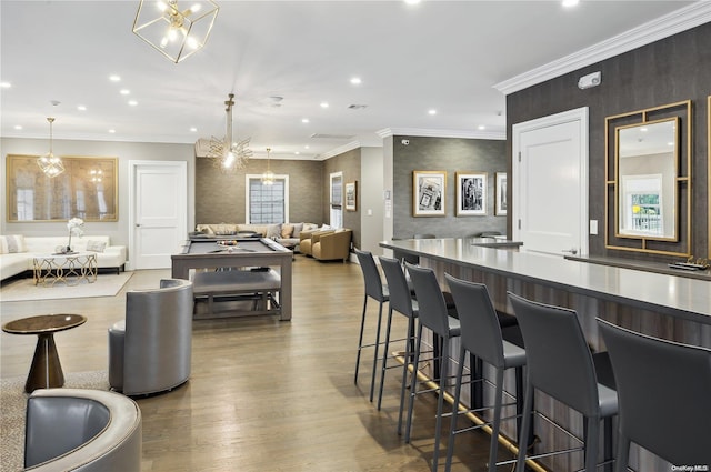 kitchen featuring crown molding, decorative light fixtures, light hardwood / wood-style flooring, a notable chandelier, and a breakfast bar area