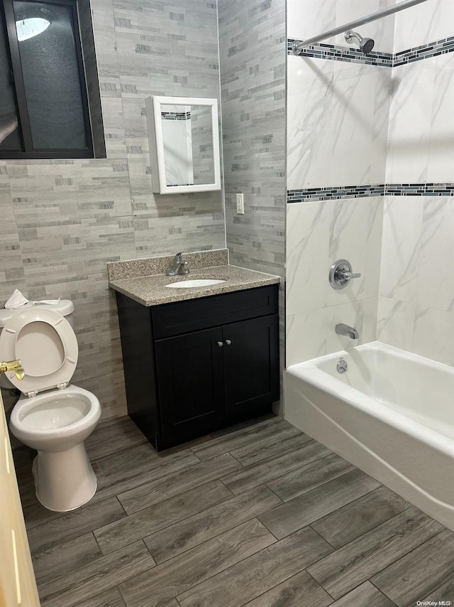 full bathroom featuring hardwood / wood-style flooring, toilet, vanity, and tiled shower / bath