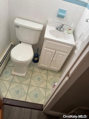 bathroom featuring tasteful backsplash, vanity, a baseboard radiator, and toilet