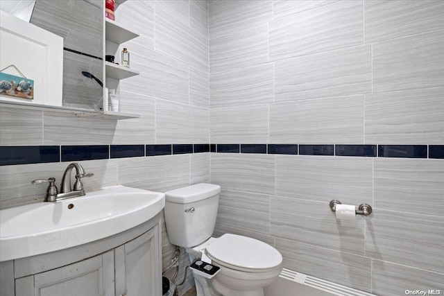 bathroom with vanity, toilet, and tile walls