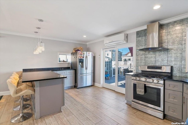 kitchen with wall chimney exhaust hood, stainless steel appliances, a wall unit AC, pendant lighting, and a kitchen bar