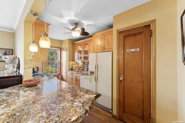 kitchen featuring tasteful backsplash, white appliances, wood-type flooring, stone countertops, and hanging light fixtures