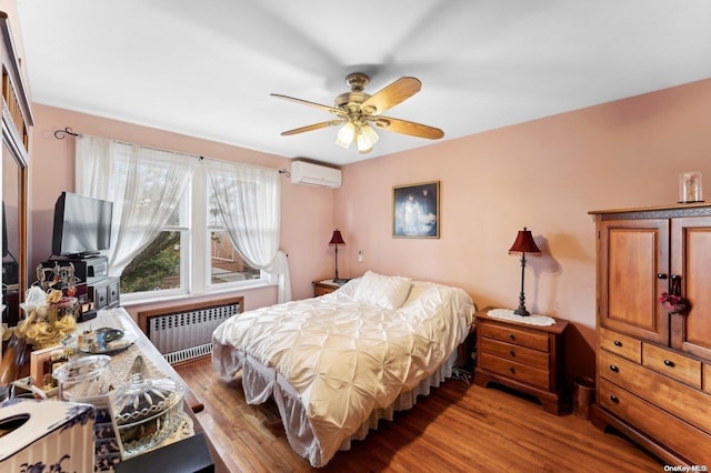 bedroom featuring ceiling fan, light hardwood / wood-style floors, a wall unit AC, and radiator