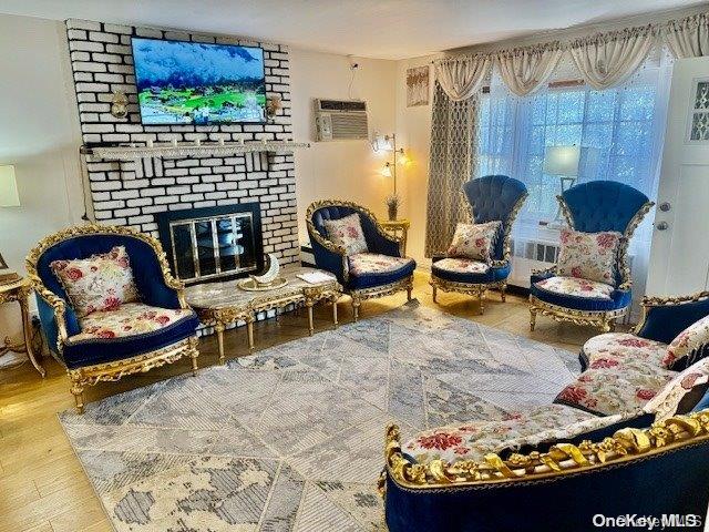 living room featuring a fireplace, hardwood / wood-style flooring, an AC wall unit, and radiator