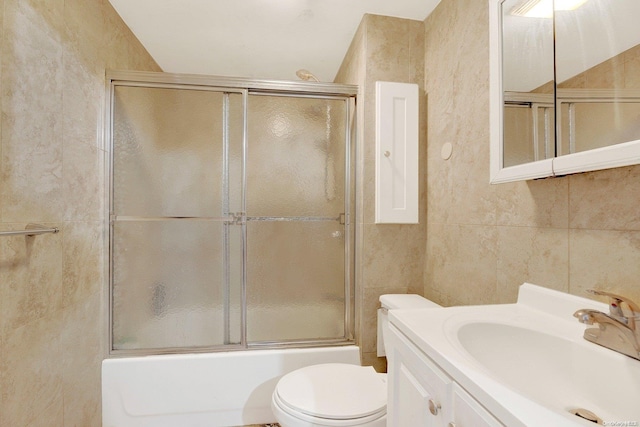 full bathroom with vanity, bath / shower combo with glass door, tile walls, and toilet