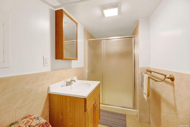 bathroom with an enclosed shower, vanity, and tile walls