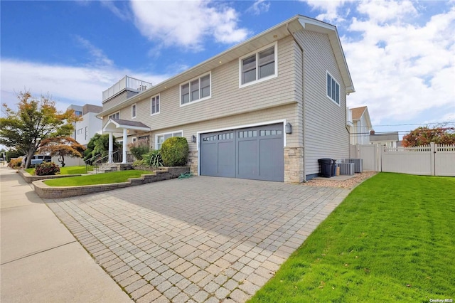 view of front of home with central air condition unit, a front lawn, and a garage