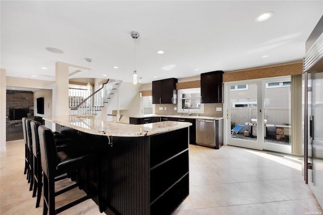 kitchen with pendant lighting, dishwasher, a breakfast bar, decorative backsplash, and light stone counters