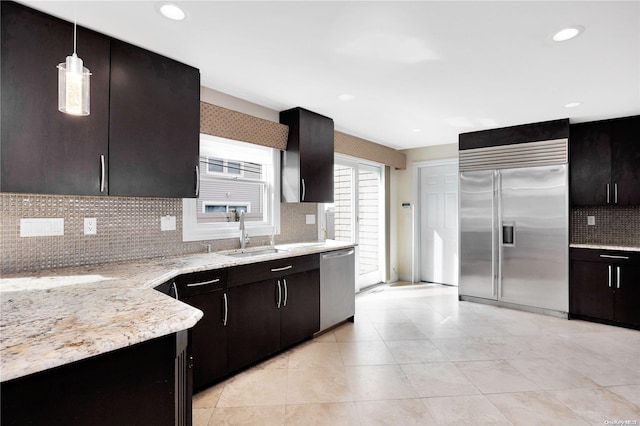 kitchen with decorative backsplash, appliances with stainless steel finishes, pendant lighting, and sink