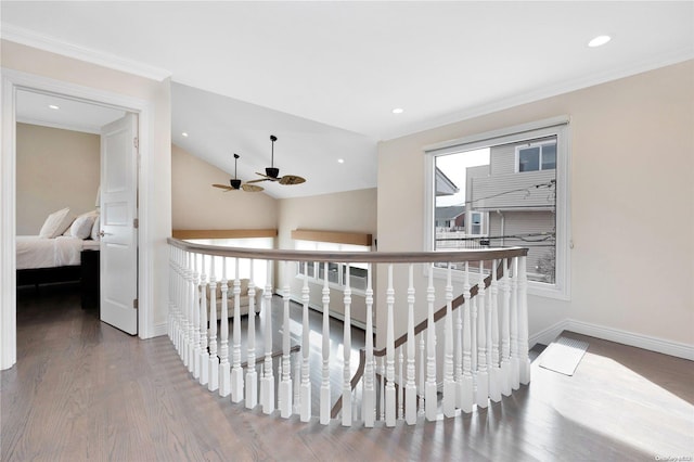 hallway with wood-type flooring, vaulted ceiling, a wealth of natural light, and ornamental molding