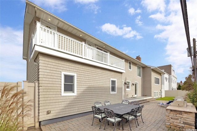 rear view of house with an outdoor kitchen, a balcony, and a patio